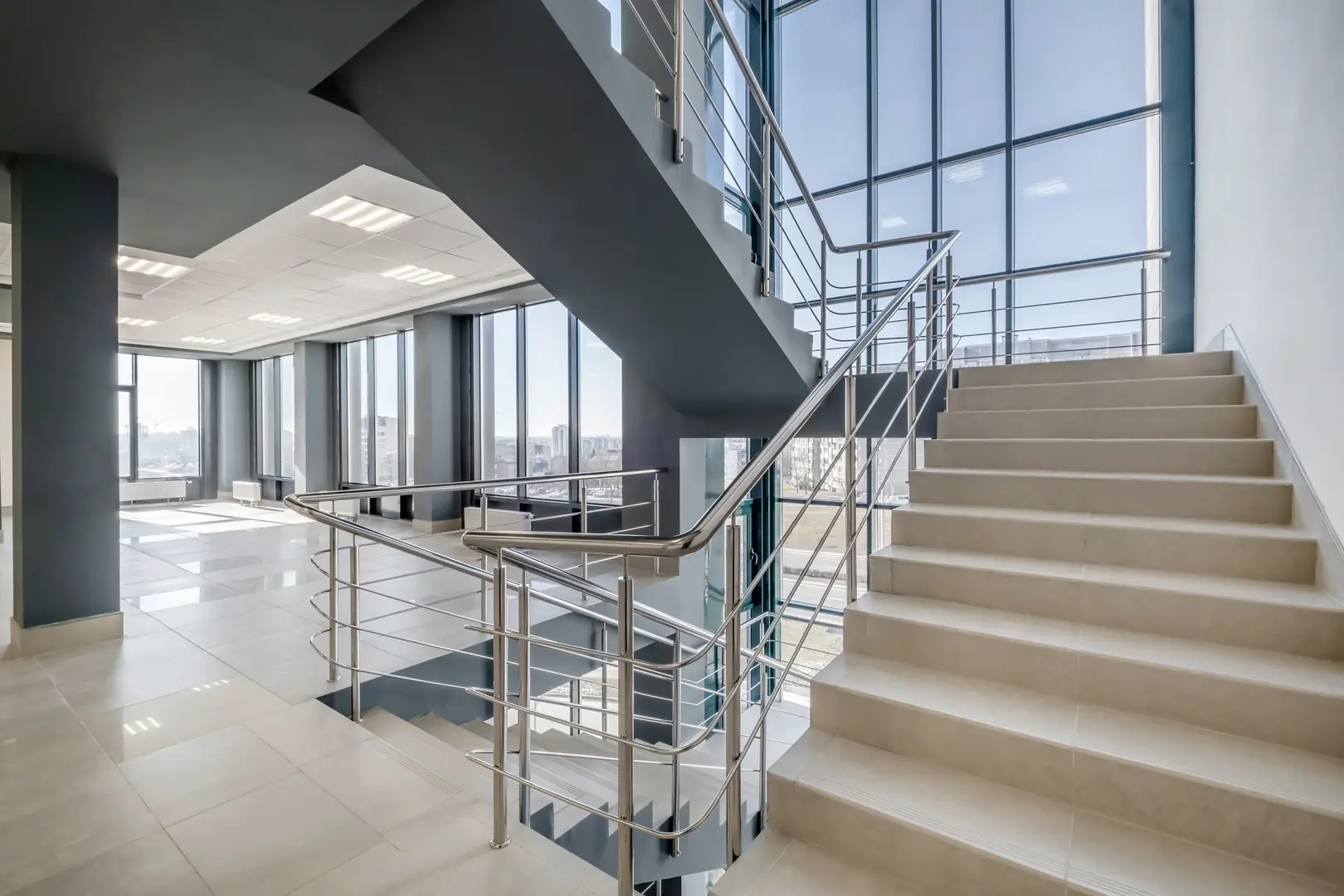 Spacious office interior with large windows and stainless-steel staircase