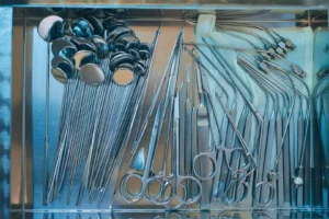 Array of stainless steel medical instruments including scissors, scalpels, and mirrors neatly arranged for surgical use.