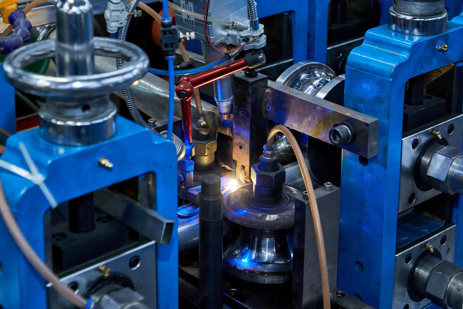 Close-up of high-speed industrial tube forming machine with precise welding equipment and blue metallic components